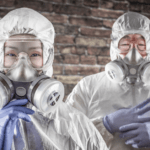Two people in hazmat suits and gas masks standing in front of a brick wall because of China pneumonia outbreak.