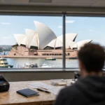 Sydney Opera House seen through a visa centre window, with a passport and fingerprint scanner on the desk.