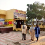 Elderly couple walking towards an Ayushman Bharat health centre with a family member