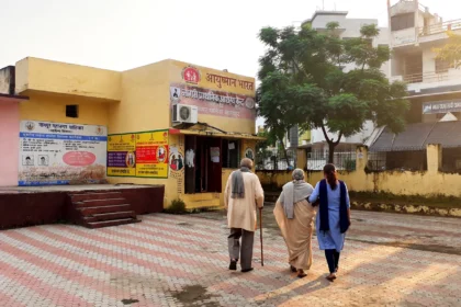 Elderly couple walking towards an Ayushman Bharat health centre with a family member