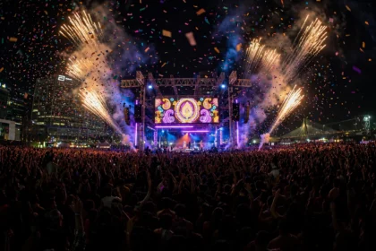 A massive night-time crowd at a Bollywood music festival stage in Mumbai, with fireworks and confetti lighting up the sky