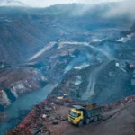 Open-cast coal mine in Jharia, Jharkhand. AI-generated image grounded in a real photo by International Accountability Project / Wikimedia Commons (CC BY 2.0).