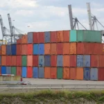 Stacked shipping containers at a busy container port.