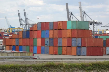 Stacked shipping containers at a busy container port.
