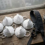 Child-size N95 masks with a school bag beside a hazy window