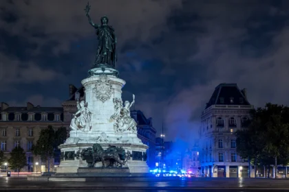 Monument a la Republique at Place de la Republique, Paris, under the overnight curfew during the October 2026 riots. Base photo: Dr. Thomas Liptak / Wikimedia Commons (CC BY-SA 4.0), news-style composite.