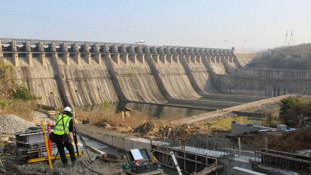 Sardar Sarovar Dam scene, based on a photo by Vijayakumarblathur / Wikimedia Commons (CC BY-SA 4.0).