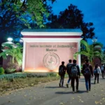 IIT Madras campus main gate at dusk, with students walking towards it.