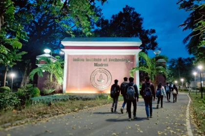 IIT Madras campus main gate at dusk, with students walking towards it.