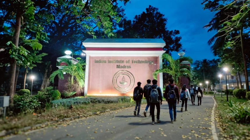 IIT Madras campus main gate at dusk, with students walking towards it.