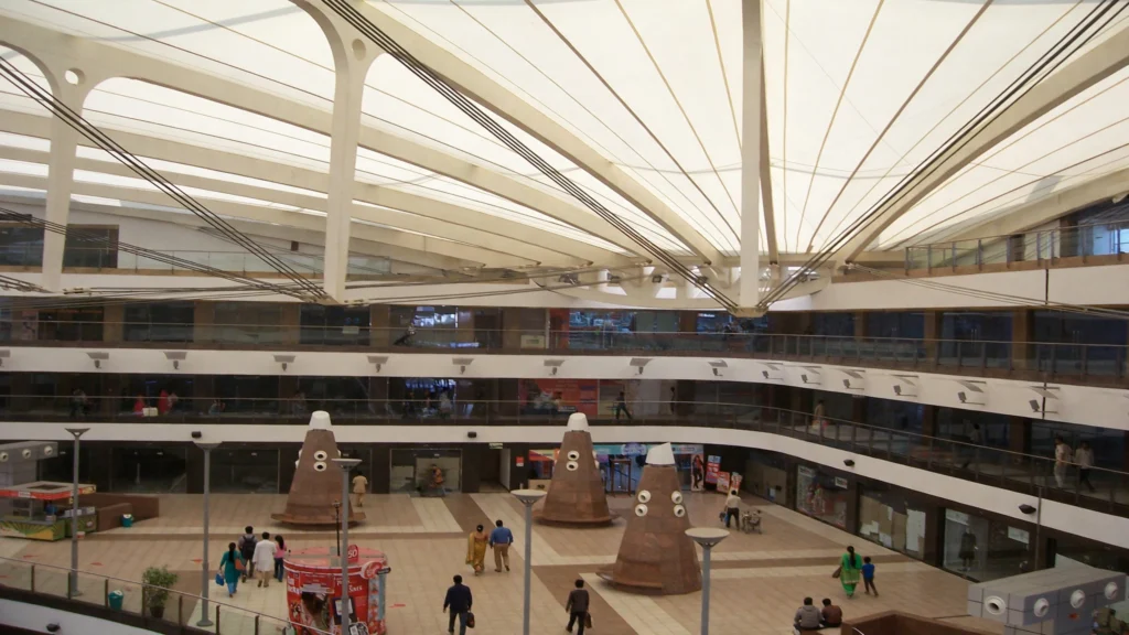 Shoppers inside a busy Delhi shopping mall, illustrative image grounded in a real photo by Justin Morgan, Wikimedia Commons