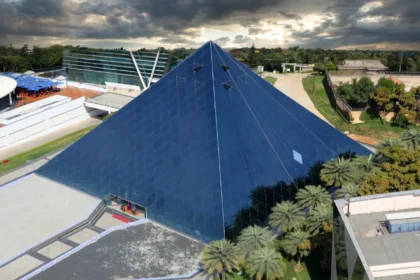 The glass pyramid of the Infosys campus in Bengaluru. Photo: Vinu Thomas / Wikimedia Commons (CC BY-SA 2.0), background composite.
