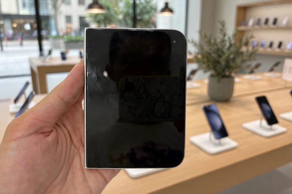 iPhone Duo foldable smartphone held at a retail store. Editorial composite based on a photo by Chino Futaba via Wikimedia Commons (CC BY-SA 4.0).
