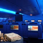 Air India amenity kit with loungewear on a business-class seat in a cabin with blue mood lighting.