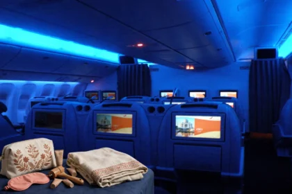 Air India amenity kit with loungewear on a business-class seat in a cabin with blue mood lighting.