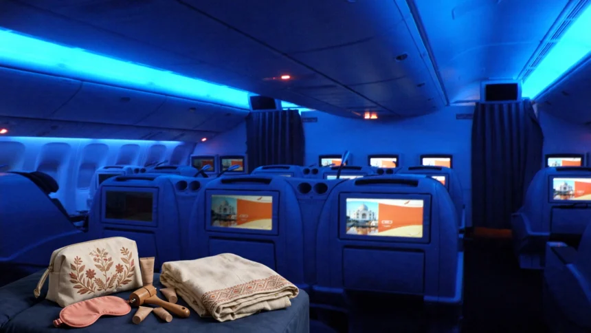 Air India amenity kit with loungewear on a business-class seat in a cabin with blue mood lighting.