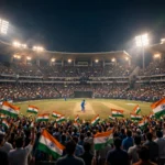 Packed night-time Indian cricket stadium with flags, batsman silhouette from behind
