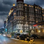 The Taj Mahal Palace, Mumbai at night. Base photograph by Mike from Vancouver, Canada via Wikimedia Commons (CC BY-SA 2.0); AI editorial composite.