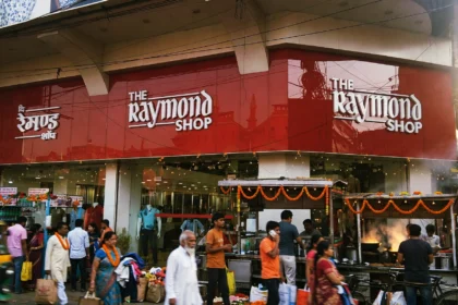 The Raymond Shop storefront in Kolkata, with shoppers outside during the festive season. Photo: Innocentbunny / Wikimedia Commons, CC BY-SA 3.0 (background composite)
