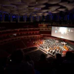 Orchestra performing live to a giant screen in the Royal Albert Hall auditorium during Sholay in Concert