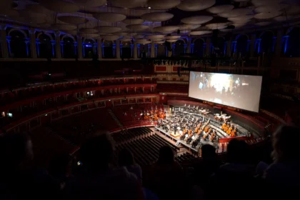 Orchestra performing live to a giant screen in the Royal Albert Hall auditorium during Sholay in Concert