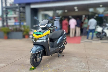 TVS iQube electric scooter outside a dealership in India. AI image grounded in a real photo by Maneesh Sreekariyam, CC BY-SA 4.0, via Wikimedia Commons.