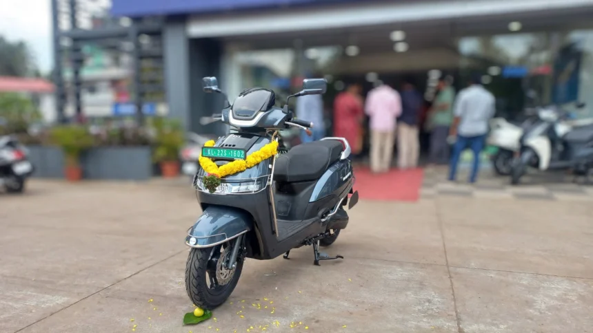 TVS iQube electric scooter outside a dealership in India. AI image grounded in a real photo by Maneesh Sreekariyam, CC BY-SA 4.0, via Wikimedia Commons.