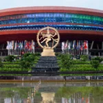 Bharat Mandapam in New Delhi, venue of ESTIC 2026. Image grounded in a real photo: Ministry of Culture / Wikimedia Commons (GODL-India), AI editorial rendering.
