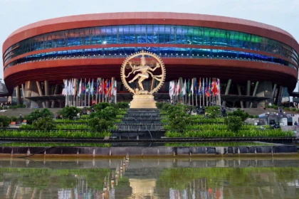 Bharat Mandapam in New Delhi, venue of ESTIC 2026. Image grounded in a real photo: Ministry of Culture / Wikimedia Commons (GODL-India), AI editorial rendering.