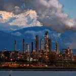 Oil refinery at dusk. AI image grounded in a real photo by Walter Siegmund, Wikimedia Commons, CC BY 2.5.