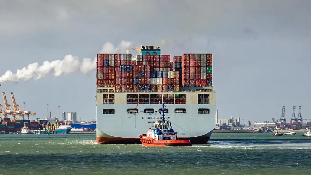 Container ship at a port. AI image grounded in a real photo by Frans Berkelaar, Wikimedia Commons, CC BY 2.0.